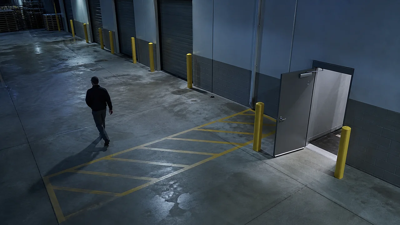 Simulated warehouse camera view with a person near a propped-open door