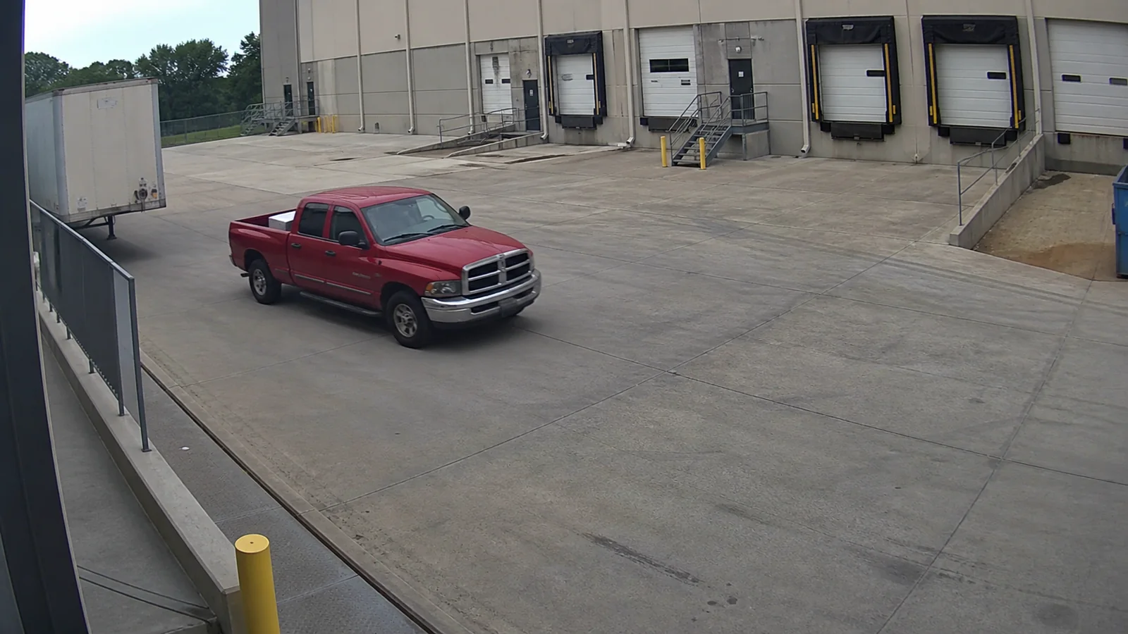 Simulated loading dock security-camera view showing a red pickup truck entering