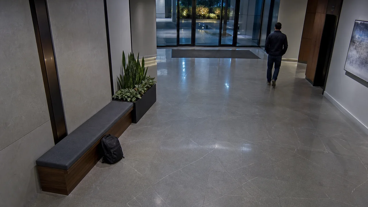 Simulated lobby camera view with an unattended backpack and a departing person